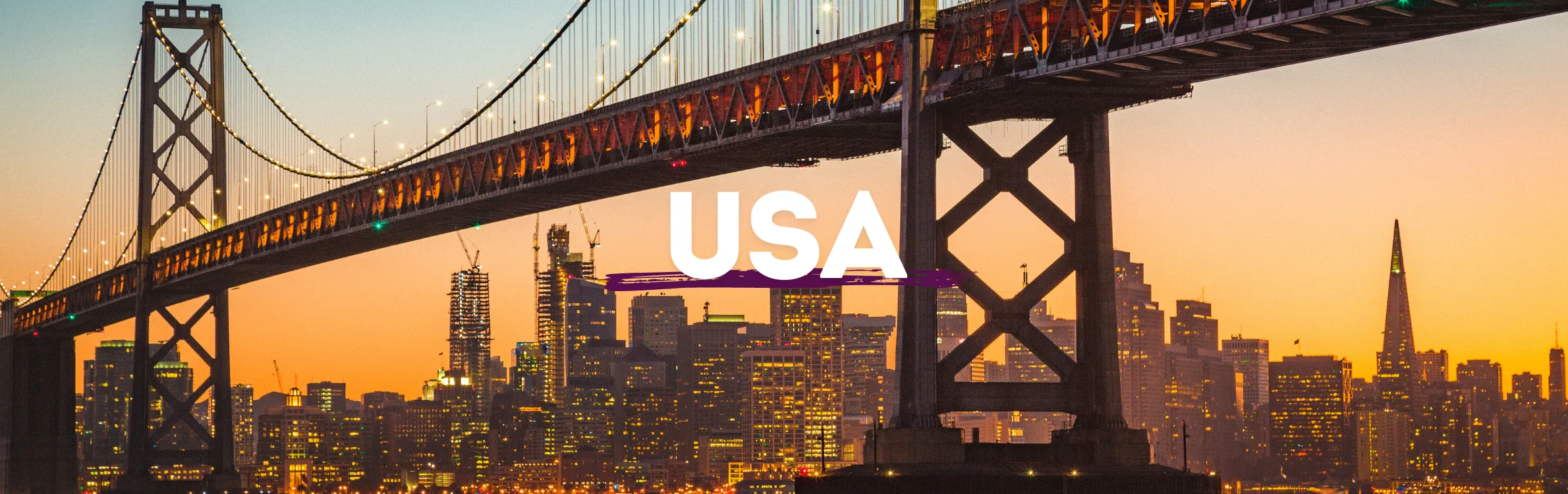 Brücke in den USA mit Skyline und Sonnenuntergang im Hintergrund